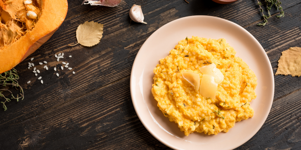 Table top with ingredients for pumpkin risotto next to a bowl of fully cooked pumpkin risotto